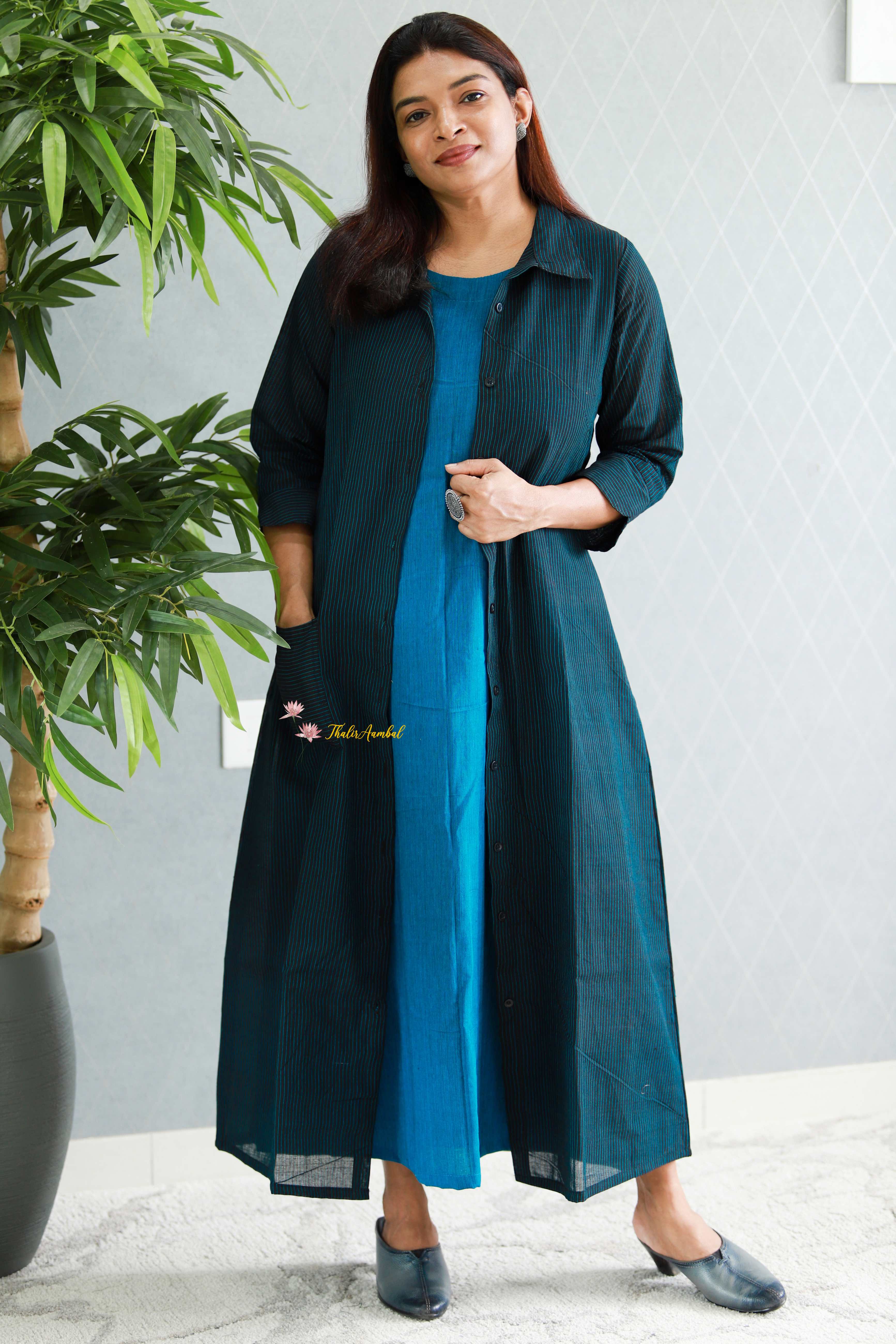 Woman wearing a teal dress with a plain background. Thaliraambal